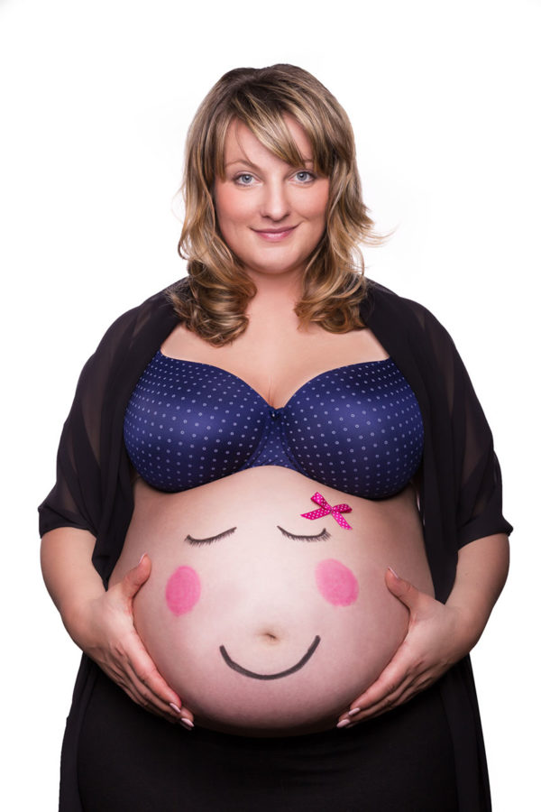 Fotograf Schwarzwald Babybauch Frau hält ihren Bauch mit aufgemaltem Smilie