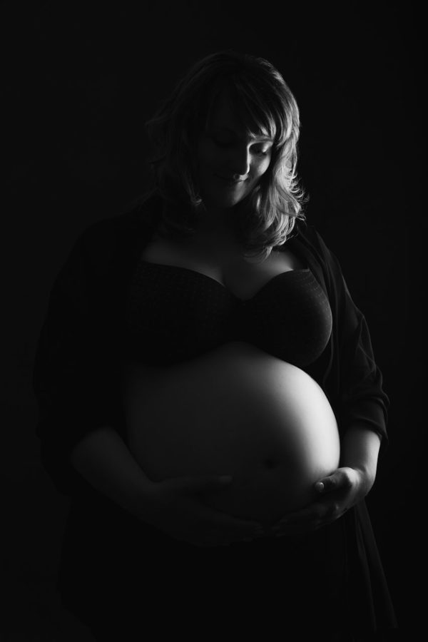 Fotograf Schwarzwald Babybauch Frau hält ihren Bauch Schwarzweiß
